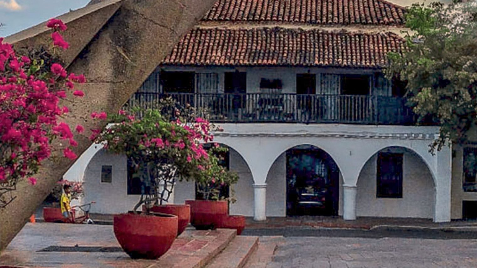 Una casa colonial del centro de Valledupar con buganvilias rosadas en la entrada.